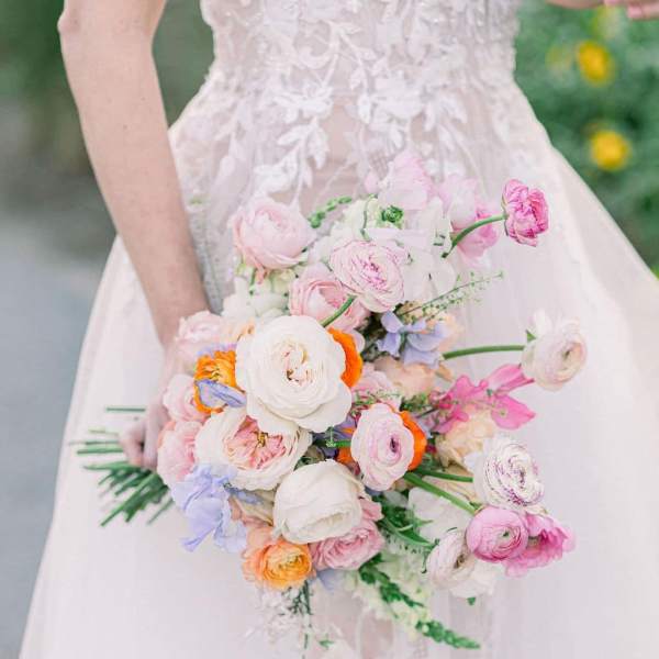 Bride holding a pastel bouquet of pink, white, and orange flowers