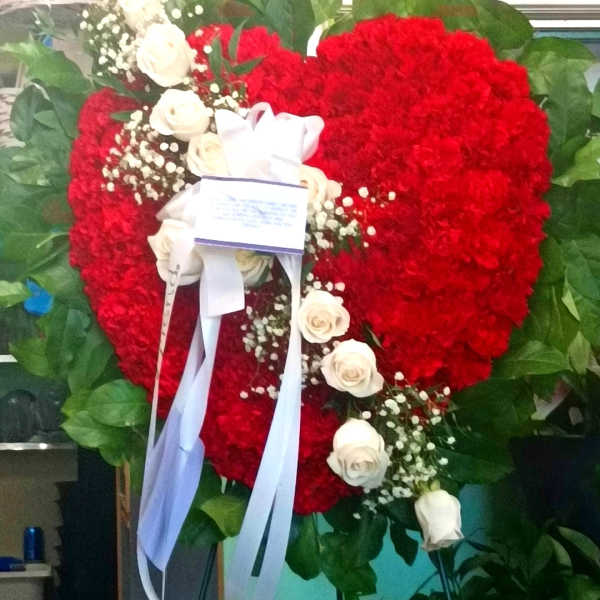 Heart-shaped red floral wreath with white roses and ribbon