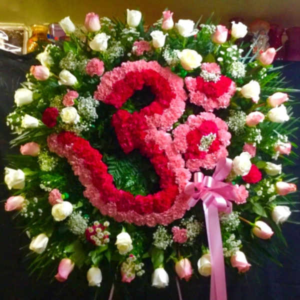 Large floral wreath with pink and white roses and a pink ribbon bow