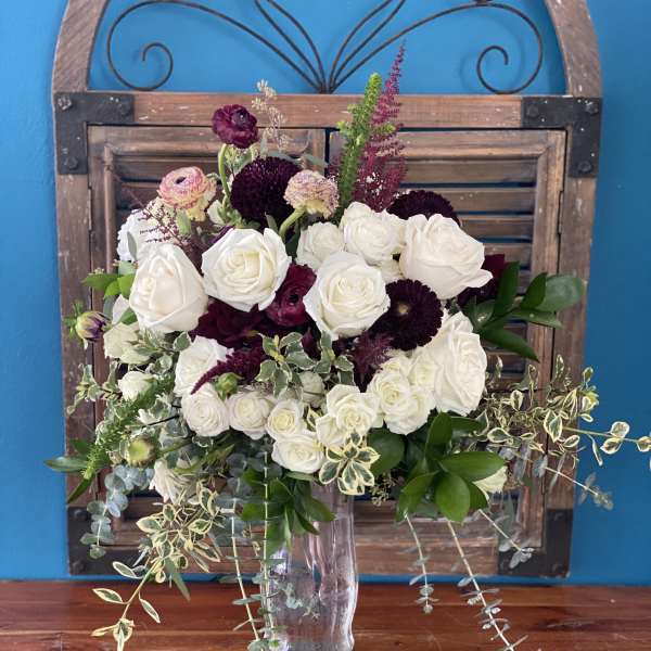 White and burgundy rose bouquet in a clear glass vase