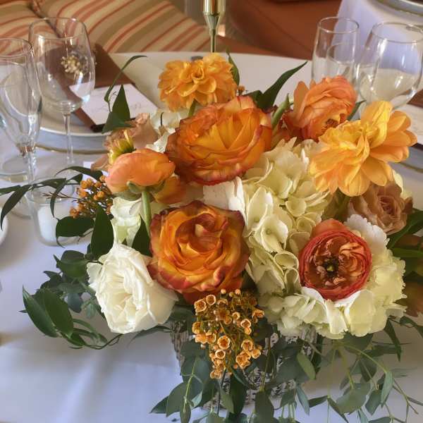 Orange and white floral centerpiece on a dining table