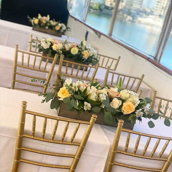Low floral centerpiece with peach and white roses on a banquet table
