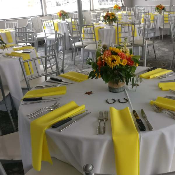 Round banquet tables with yellow napkins and floral centerpieces