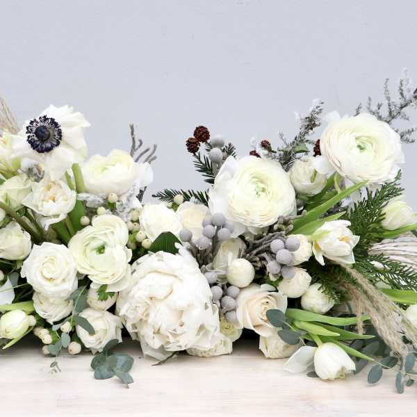 Low white floral arrangement with ranunculus and anemones
