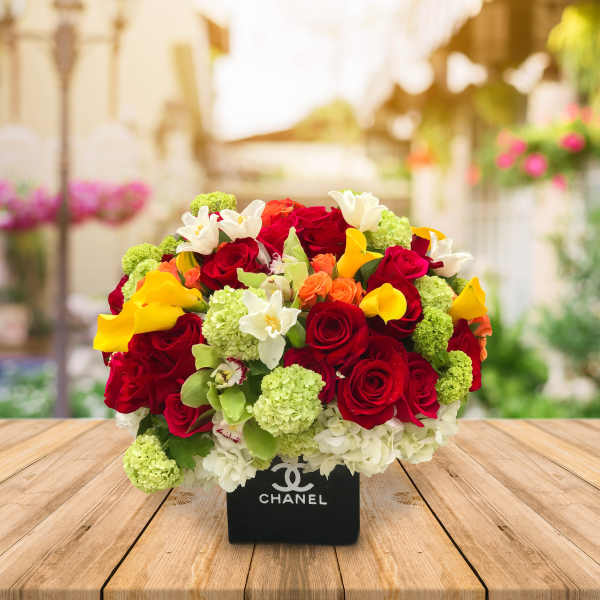 Bouquet of red roses, yellow calla lilies, and white flowers in a black box