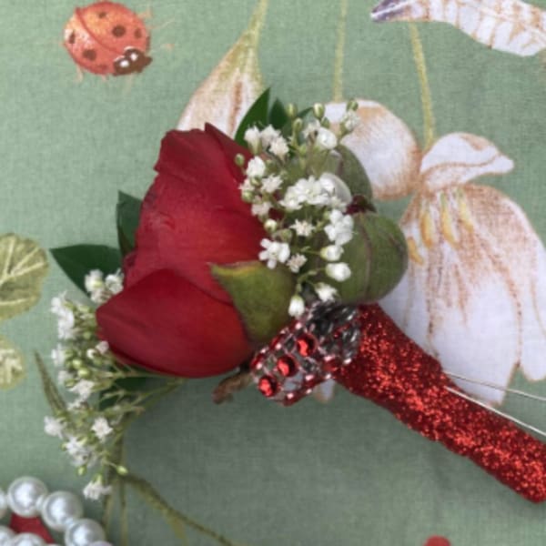Red rose boutonniere with baby's breath and a glittery red handle