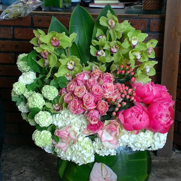 Bouquet of pink roses, green orchids, and white hydrangeas in a green vase