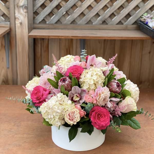 Pink and cream floral arrangement in a white round box