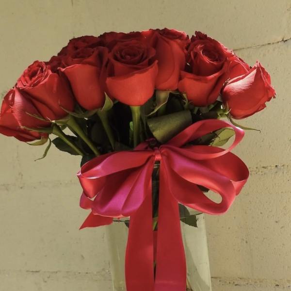 Bouquet of red roses in a glass vase with a pink ribbon