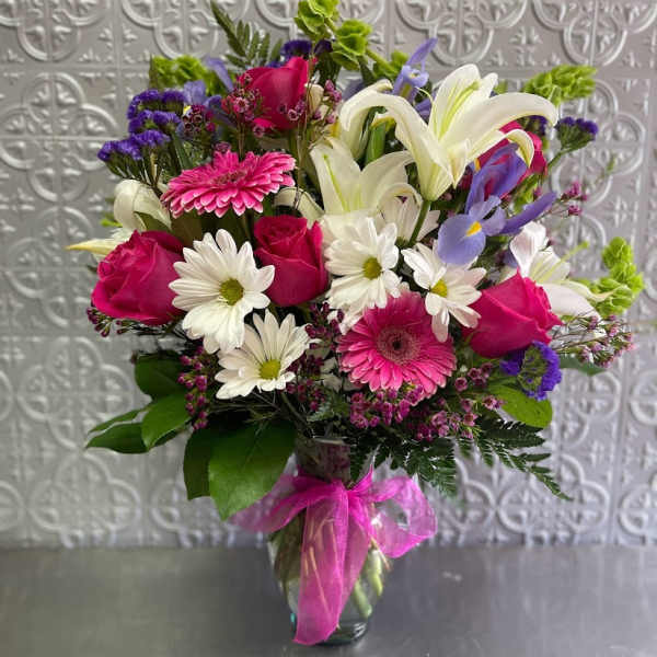 Mixed bouquet of pink, white, and purple flowers in a glass vase