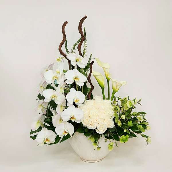 White orchids, roses, and calla lilies in a white bowl vase