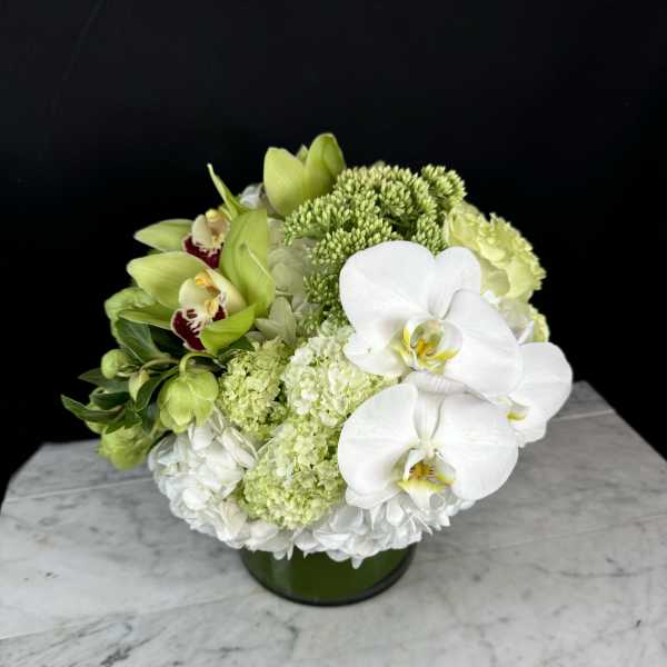 Green and white floral arrangement in a low round vase