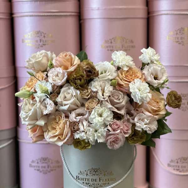 Pastel roses and carnations arranged in a round hatbox