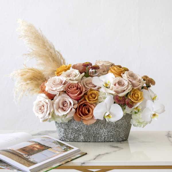 Mixed roses and white orchids in a gray container