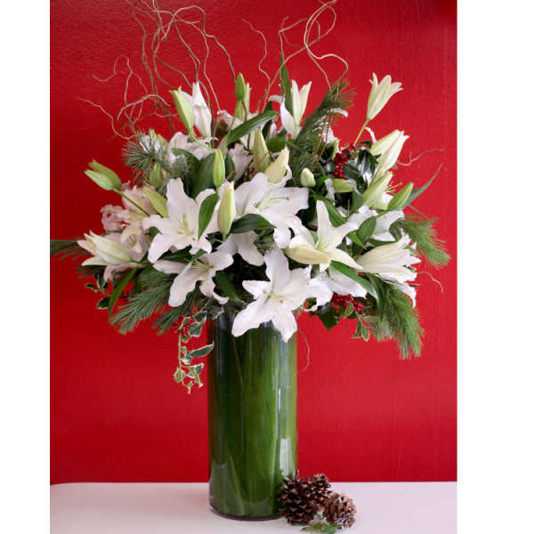 White lilies in a tall glass vase with pine accents