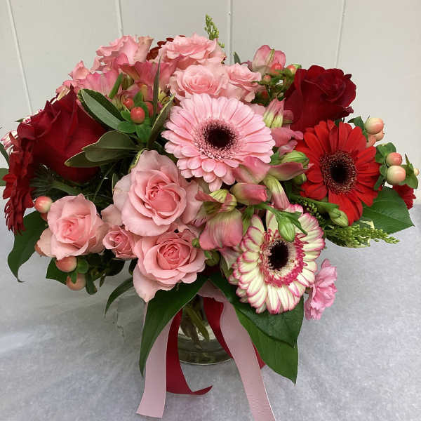 Pink and red mixed bouquet in a glass vase with ribbon
