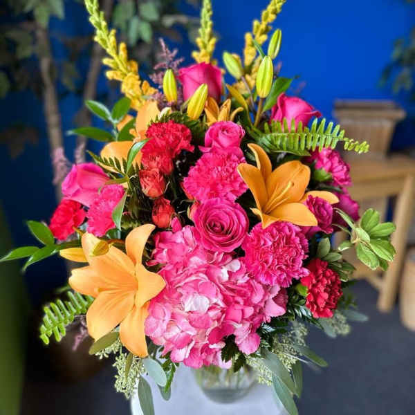 Bright pink and orange floral arrangement in a white vase