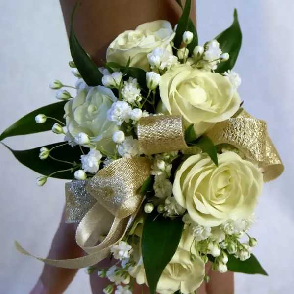 Ivory rose wrist corsage with small white blooms and gold ribbon accents.