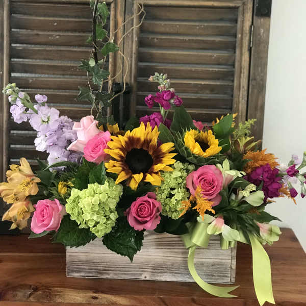 Mixed bouquet with sunflowers, pink roses, and hydrangeas in a wooden box