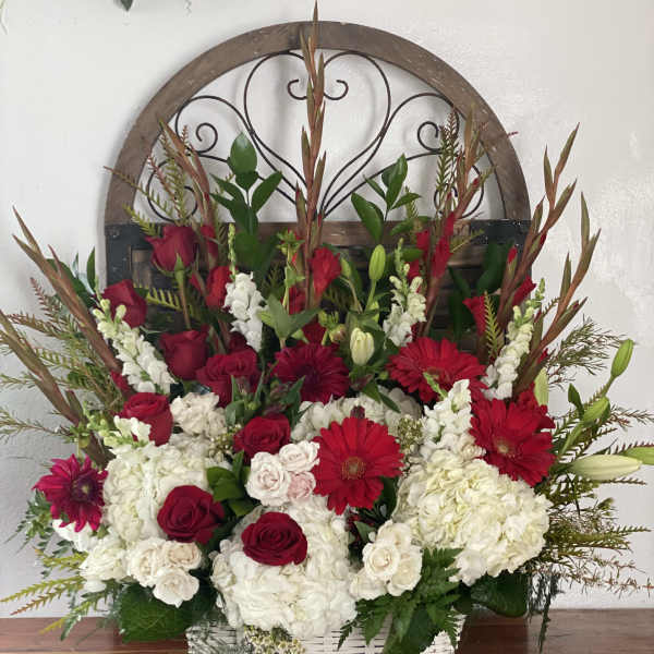 Basket arrangement of red roses, white hydrangeas, and red gerbera daisies