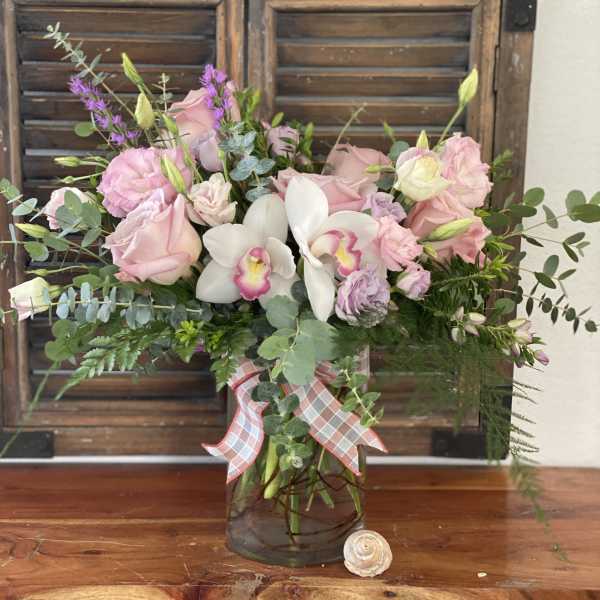 Pink and white floral arrangement in a glass vase with a plaid ribbon
