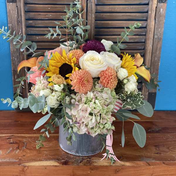 Mixed bouquet in a ribbed metal container with roses, dahlias, sunflowers, and hydrangeas