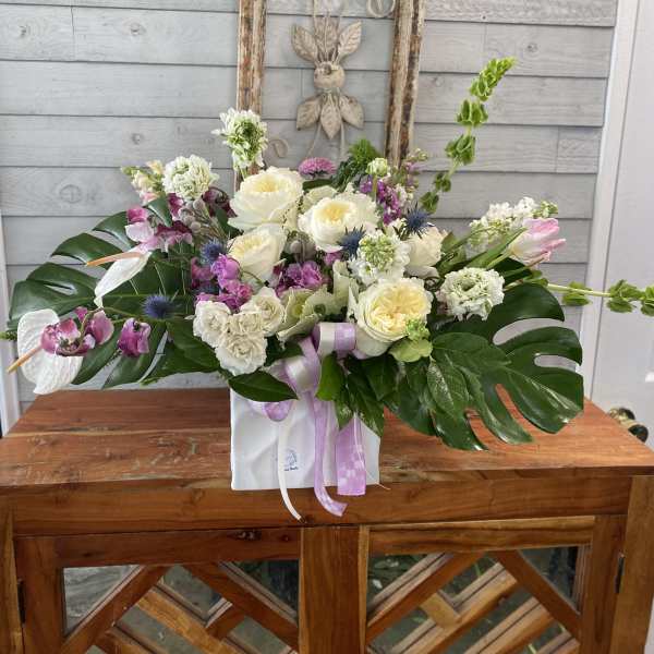 Mixed floral arrangement with white and pink blooms in a white box