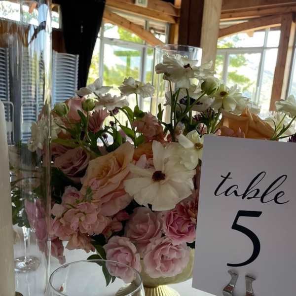Pastel floral centerpiece in a gold vase beside a table number card