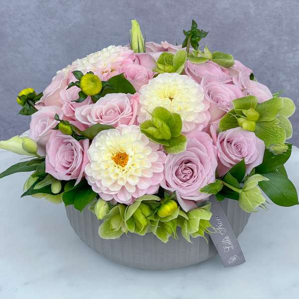 Pink roses and white blooms arranged in a gray round box
