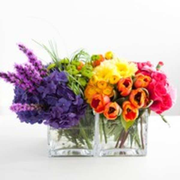 Two colorful flower arrangements in clear square vases
