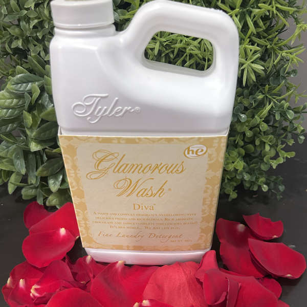 Laundry detergent bottle surrounded by red rose petals and greenery