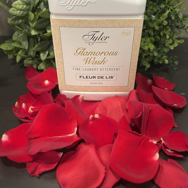 Tyler laundry detergent bottle surrounded by red rose petals and greenery