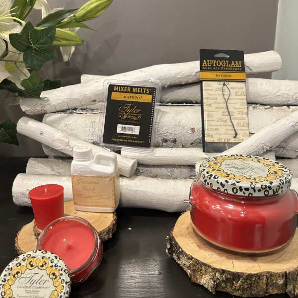 Assorted red candles and Tyler fragrance products on wood slices
