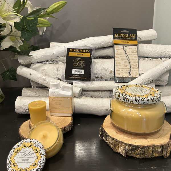 White lilies beside yellow candles and fragrance products on wood slices