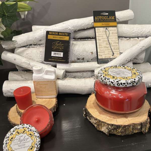 Assorted red candles and fragrance products on wood slices