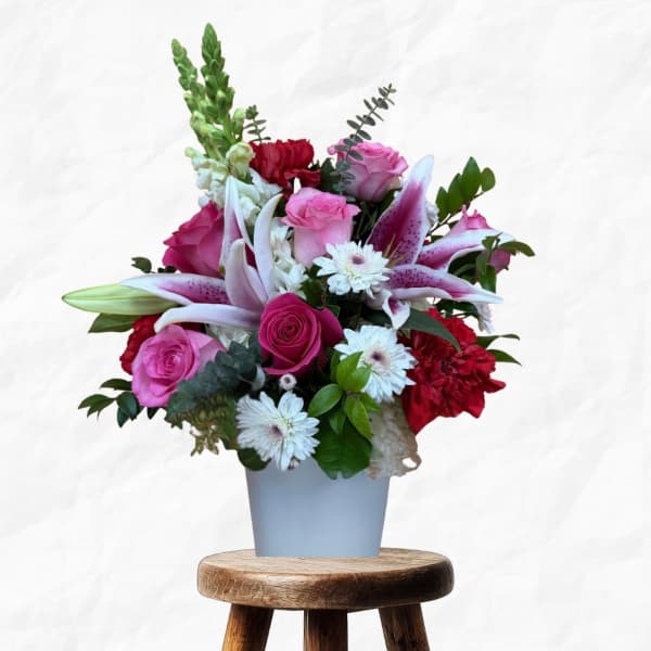 Pink and red floral arrangement in a light blue vase