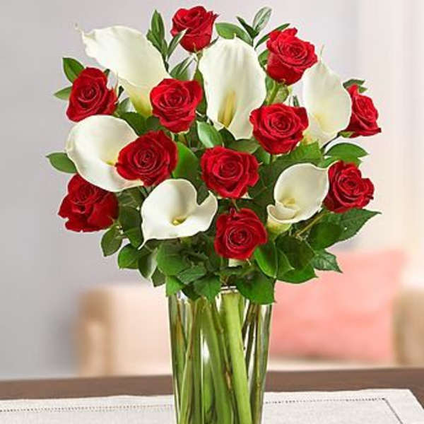 Red roses and white calla lilies in a clear glass vase