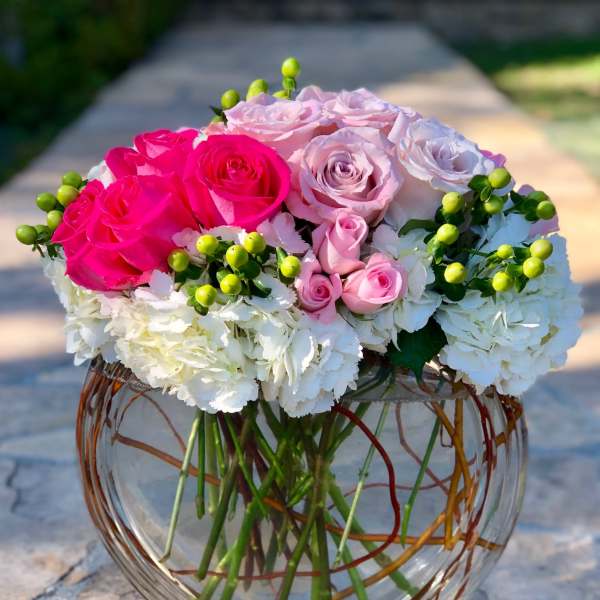 Pink and white roses in a round glass vase