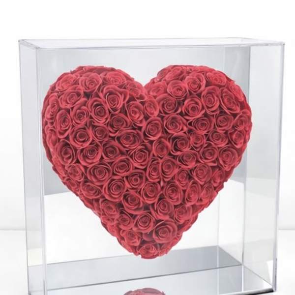 Heart-shaped arrangement of red roses in a clear display box