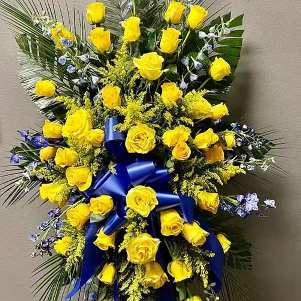 Tall yellow rose standing spray with blue ribbon and palm fronds