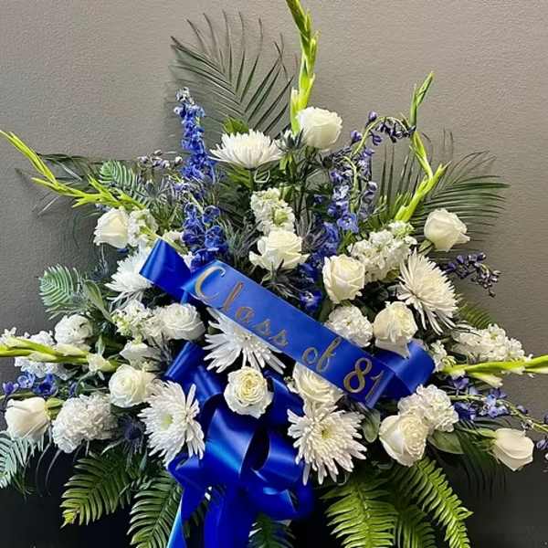 White and blue funeral spray with a blue ribbon reading "Class of 81"