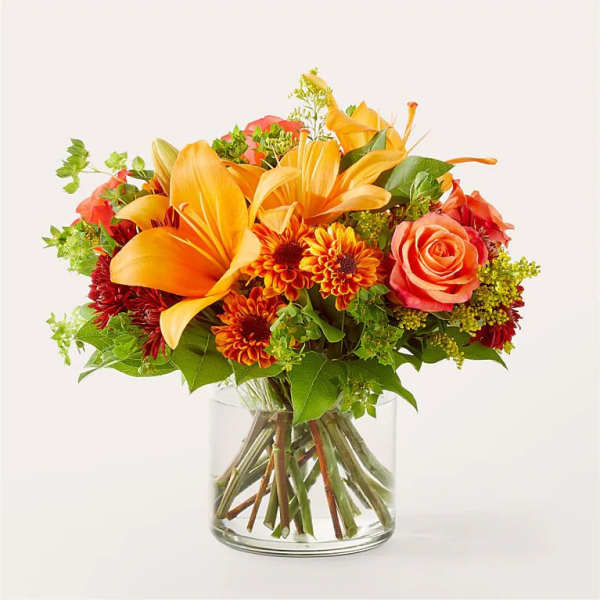 Orange lilies and roses in a clear glass vase
