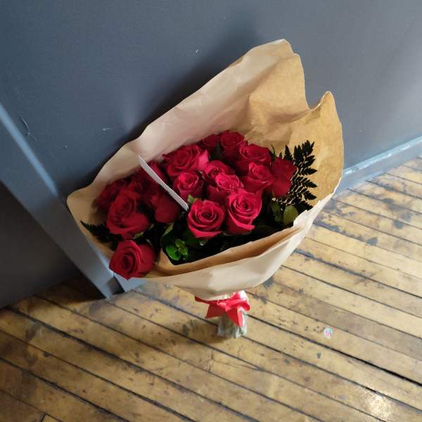 Bouquet of red roses wrapped in brown paper with a red ribbon