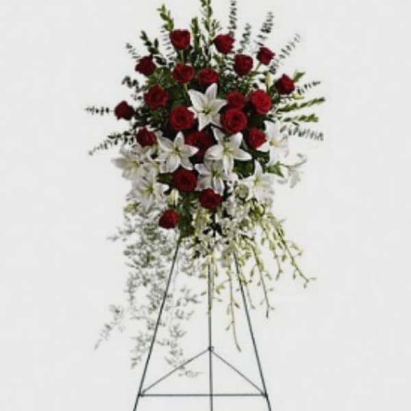 Standing floral spray with red roses and white lilies on a metal easel