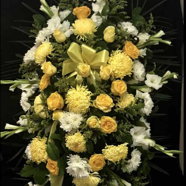 Yellow and white floral standing spray with a ribbon bow