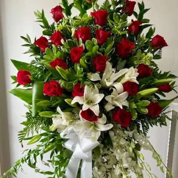 Standing spray of red roses and white lilies with a white ribbon