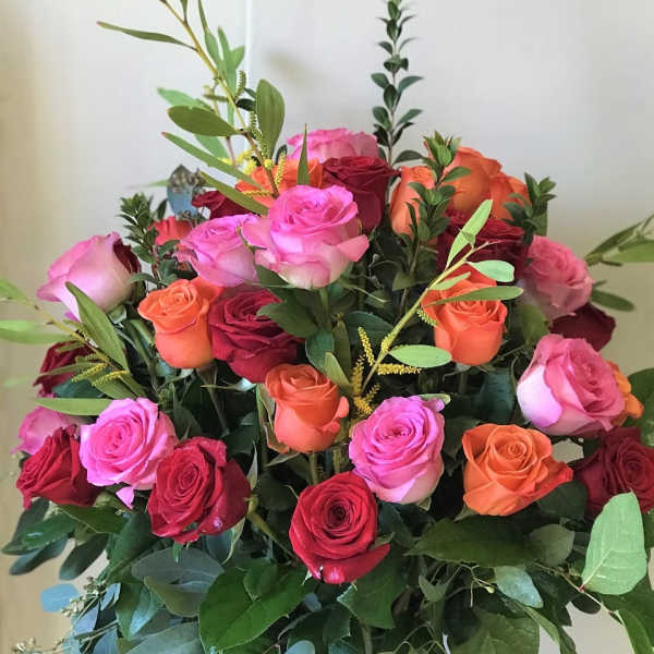 Bouquet of pink, red, and orange roses in a glass vase