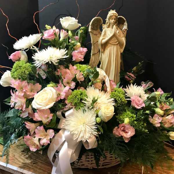 Basket of pink and white flowers with an angel figurine