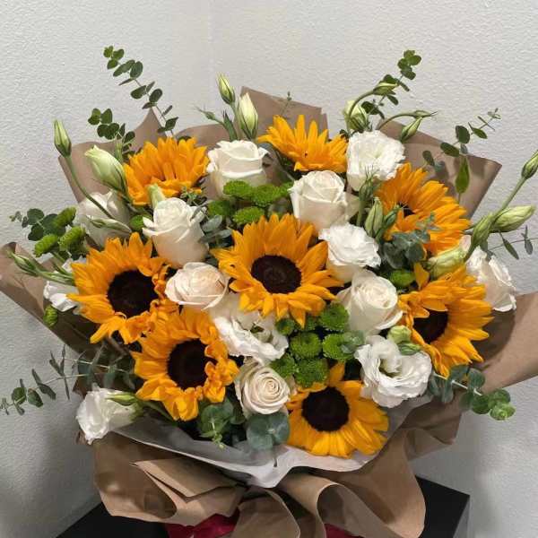 Bouquet of sunflowers and white roses wrapped in brown paper