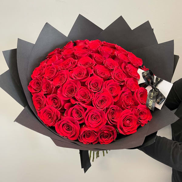 Large bouquet of red roses wrapped in black paper with a ribbon
